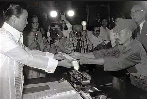 This picture taken on March 11, 1974 shows former Japanese imperial army soldier Hiroo Onoda (R) offering his military sword to former Philippine President Ferdinand Marcos to express his surrender. (JIJI PRESS/AFP/Getty Images)

