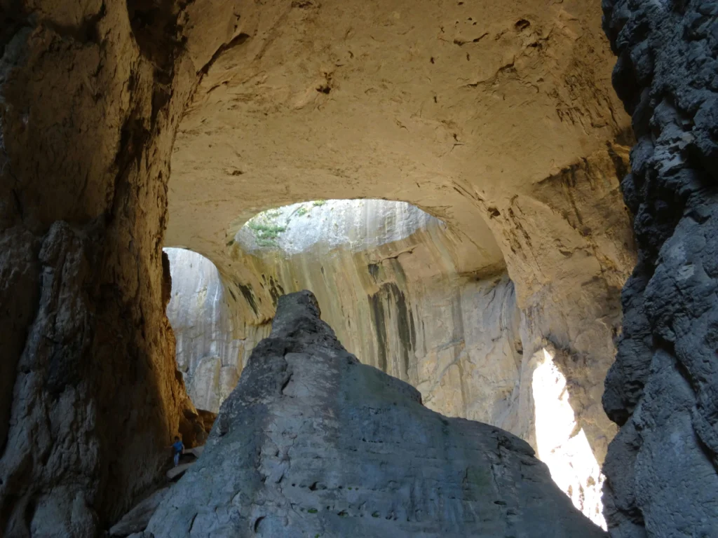 The Eyes of God in Prohodna cave. You can see a climber descending in the bottom left corner of this picture giving the sense of scale of the cave and the 'eyes'
