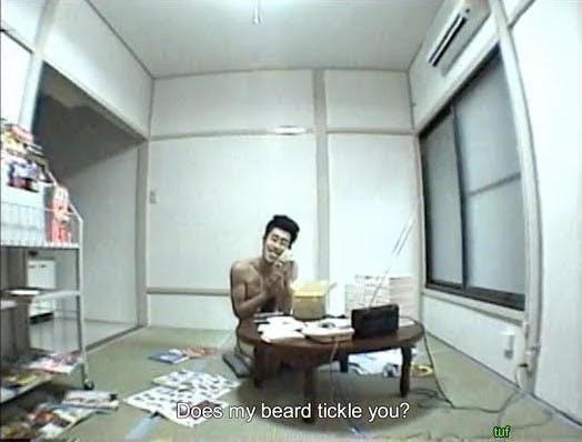 Tomoaki Hamatsu AKA Nasubi talking to a stuffed animal, in a sparse room without clothes, surrounded by magazines. He spent over 15 months in isolation like this. 